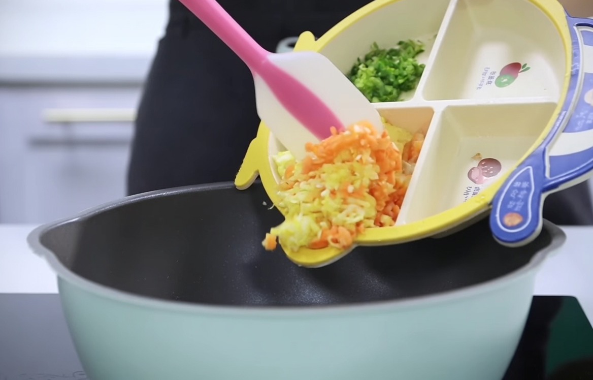 Zanahorias, patatas y apio picados vertiéndose desde un plato infantil segmentado a una olla.