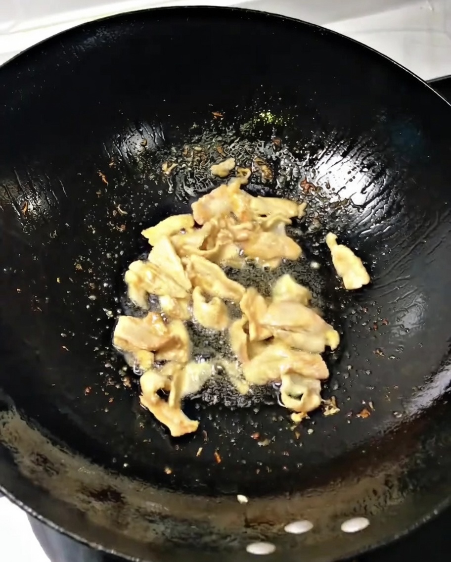 Cebolla verde y jengibre picados removiéndose junto al cerdo en un wok caliente.