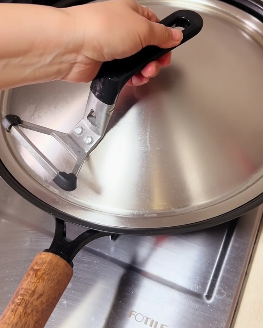 Almejas cocinándose en un wok tapado, con vapor escapando por debajo de la tapa.