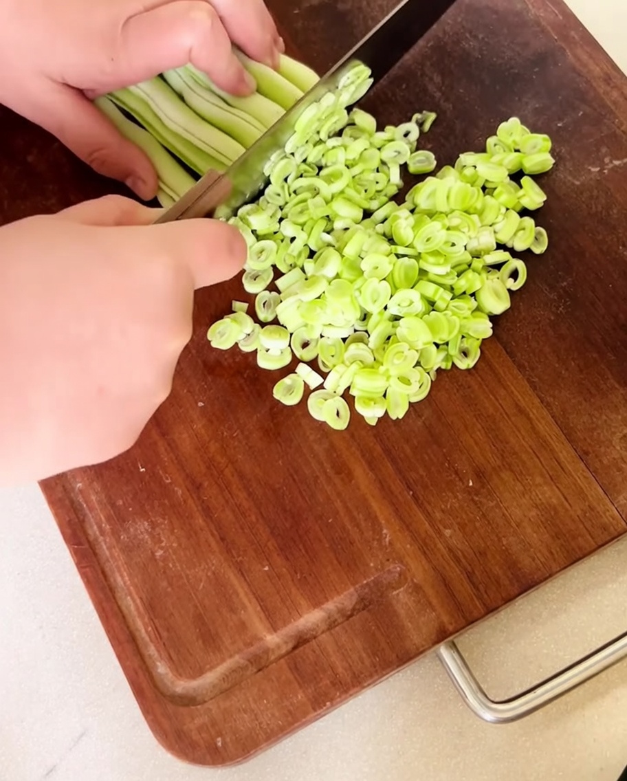 Judías verdes frescas picadas finamente extendidas en una tabla de cortar de madera.