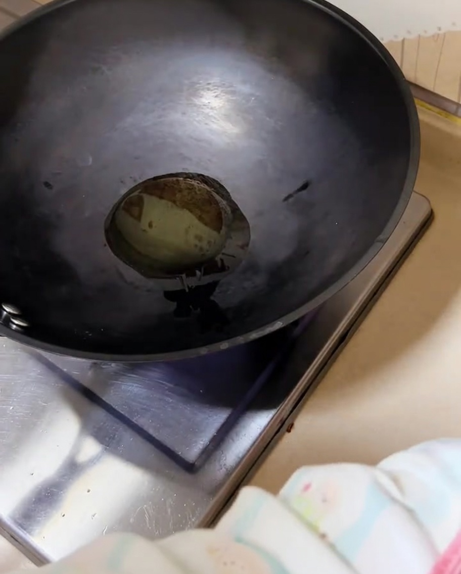 Cebollinos picados chisporroteando en un wok caliente con aceite.