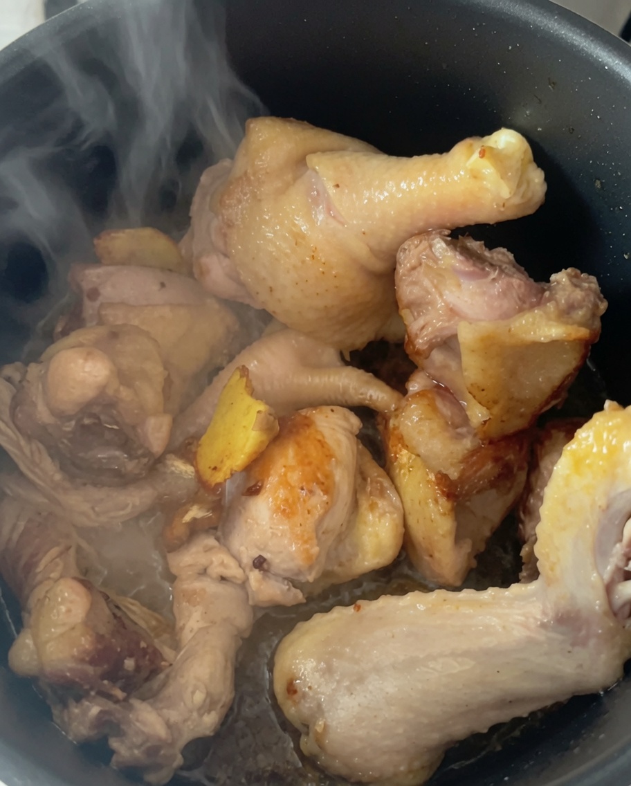 Vapor saliendo de los trozos de pollo en la olla a presión tras añadir agua caliente.