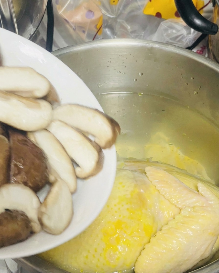 Hongos shiitake laminados siendo añadidos a la olla con la gallina.