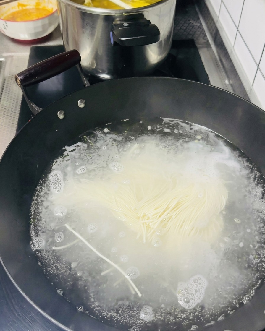 Fideos finos cayendo en una olla con agua hirviendo.