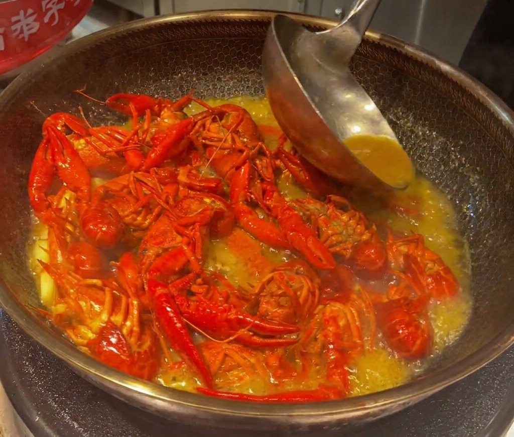 Cangrejos cocinándose a fuego lento y siendo removidos en un caldo espeso y sabroso en un wok.