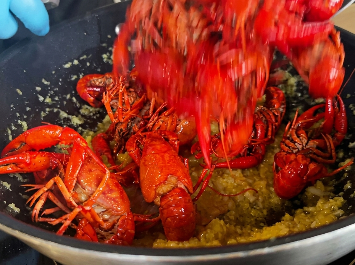 Cangrejos fritos siendo añadidos al wok que contiene la base de ajo.
