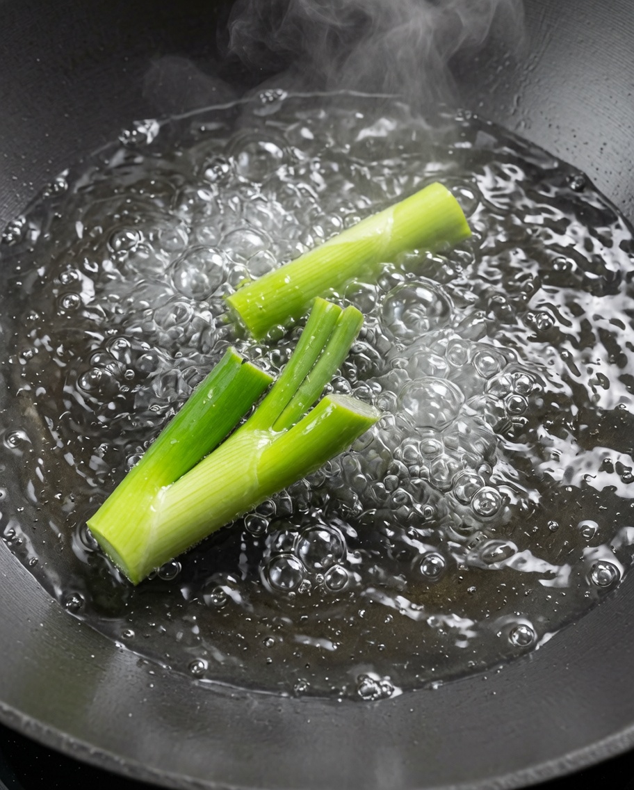 Cangrejos de río siendo escaldados en un wok grande con agua hirviendo y cebollino.