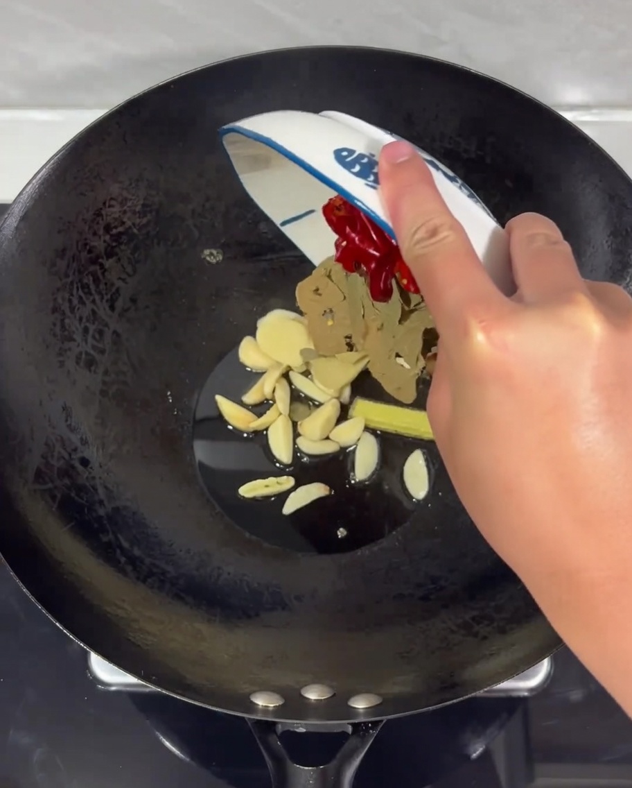 Una mezcla de jengibre, ajo y chiles secos chisporroteando en aceite caliente en un wok.