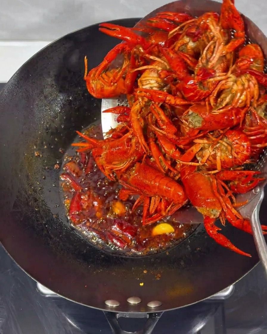 Cangrejos fritos combinándose con la salsa picante en un wok.