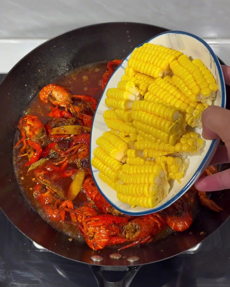Trozos de maíz dispuestos en el caldo picante con los cangrejos en un wok.