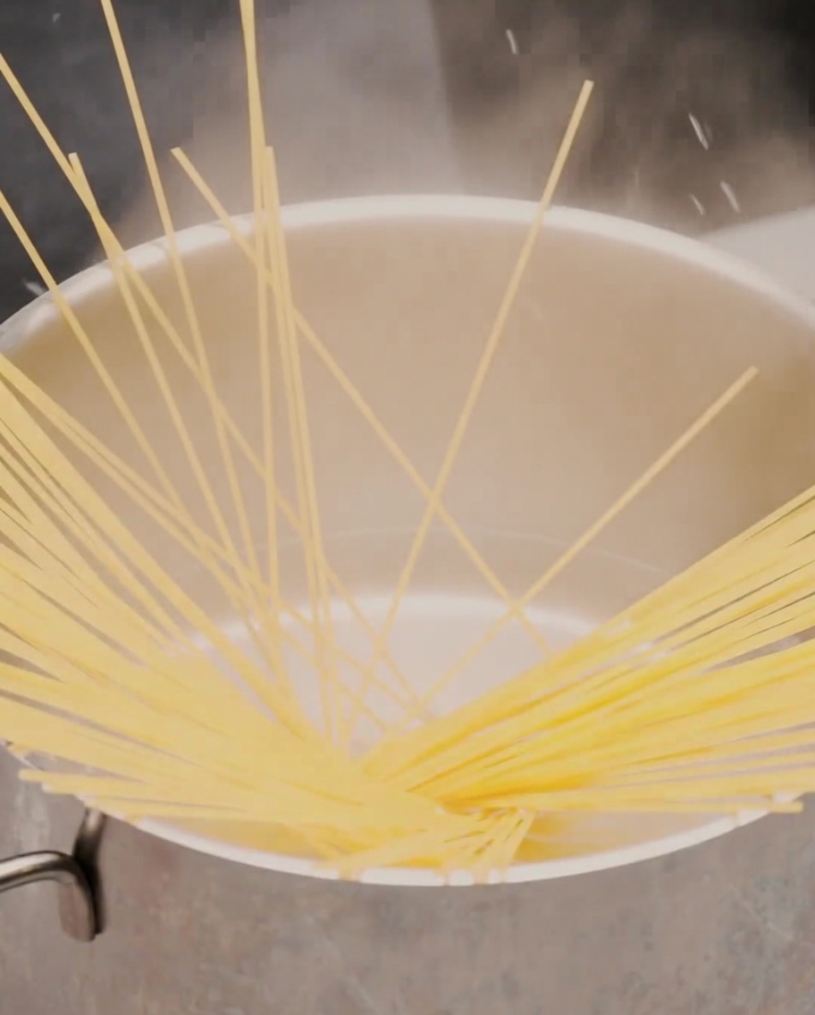 Una cucharada de pasta de ajo asado suave siendo depositada en una sartén negra.