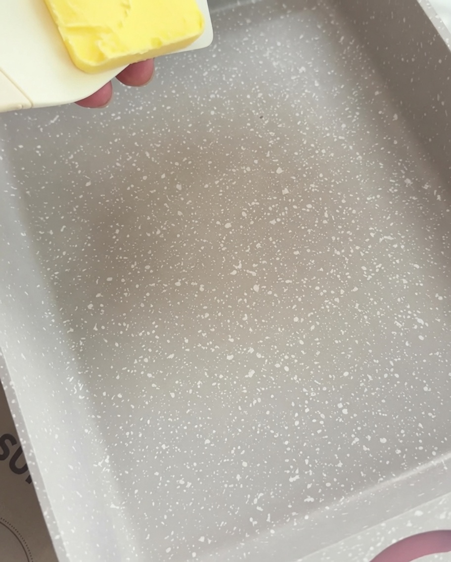 Una sartén rectangular con un trozo de mantequilla amarilla empezando a derretirse.