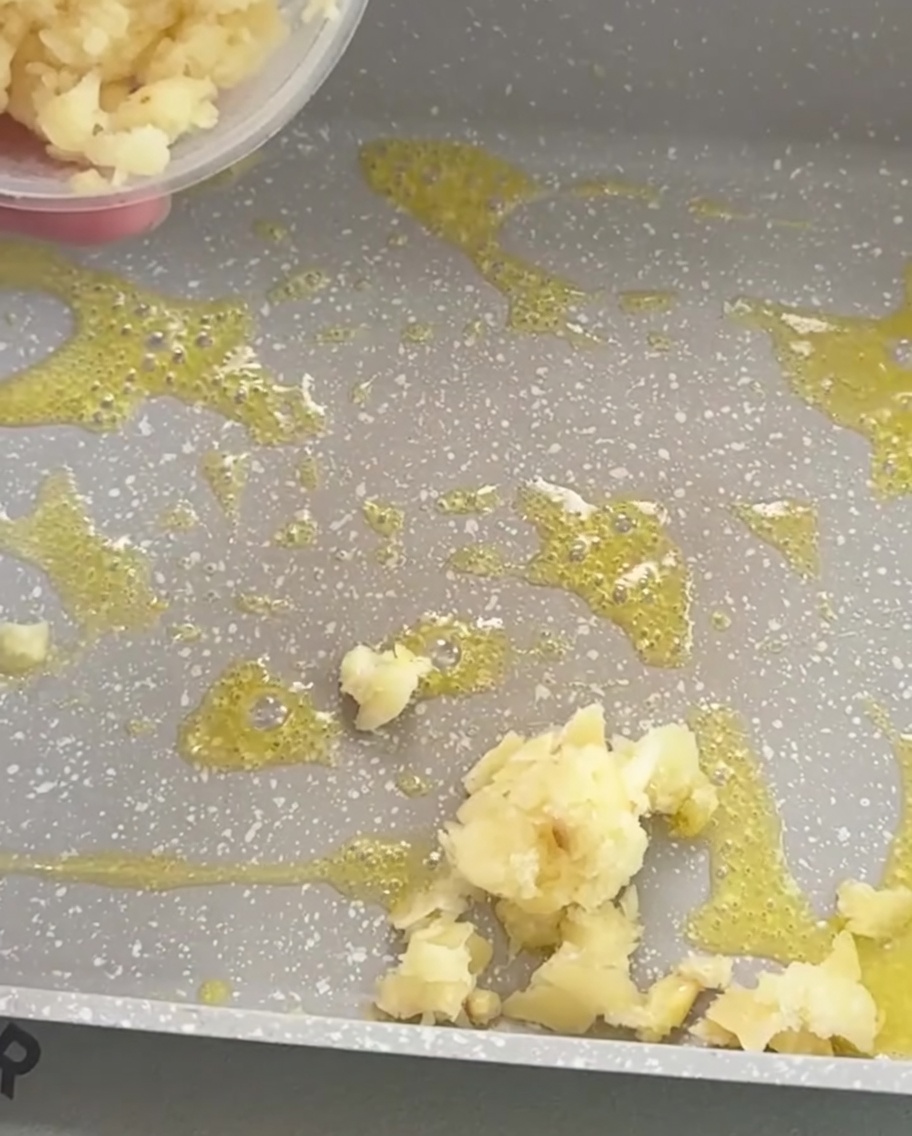 Ajo picado friéndose en mantequilla derretida dentro de una sartén, mostrando un color dorado claro.