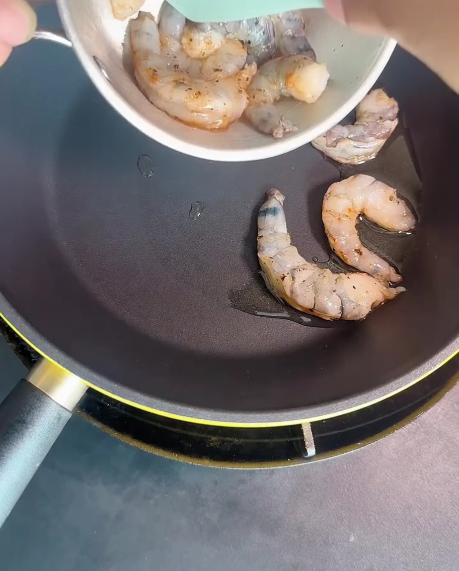 Gambas dorándose en una sartén caliente hasta volverse opacas.