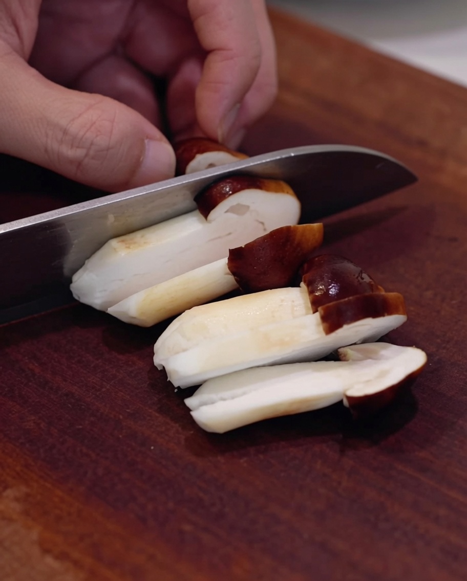 Setas shiitake frescas siendo cortadas en una tabla de madera.