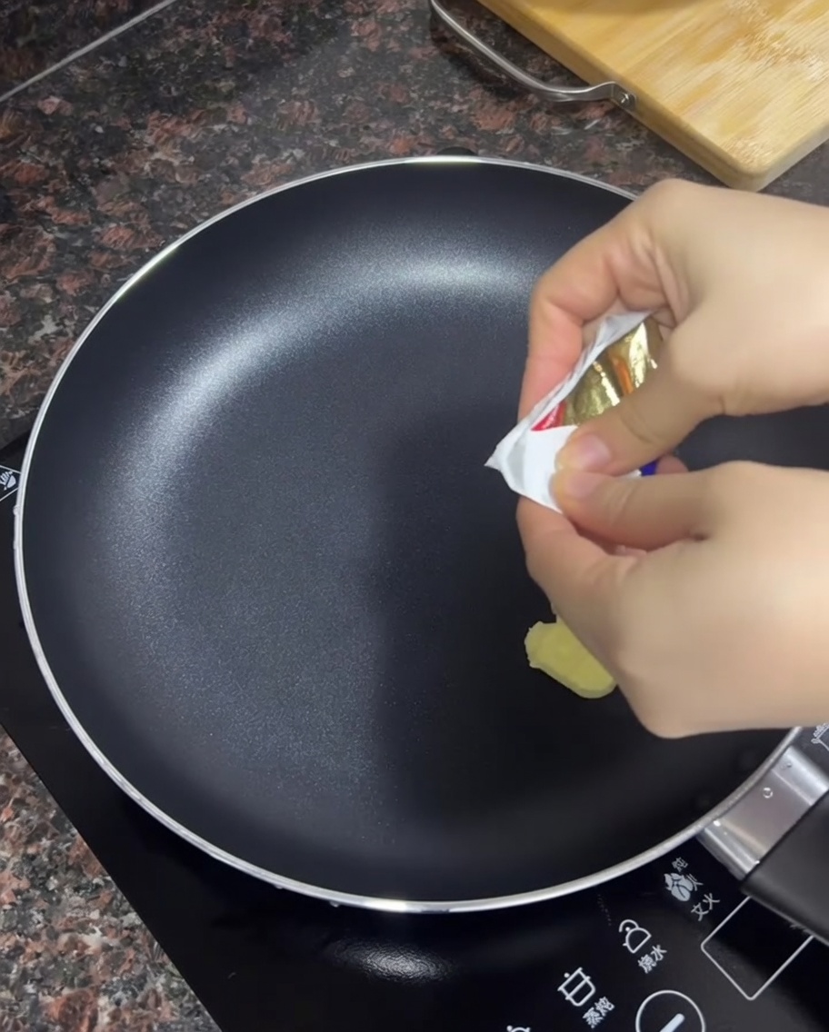Mantequilla derritiéndose en una sartén negra antiadherente caliente.