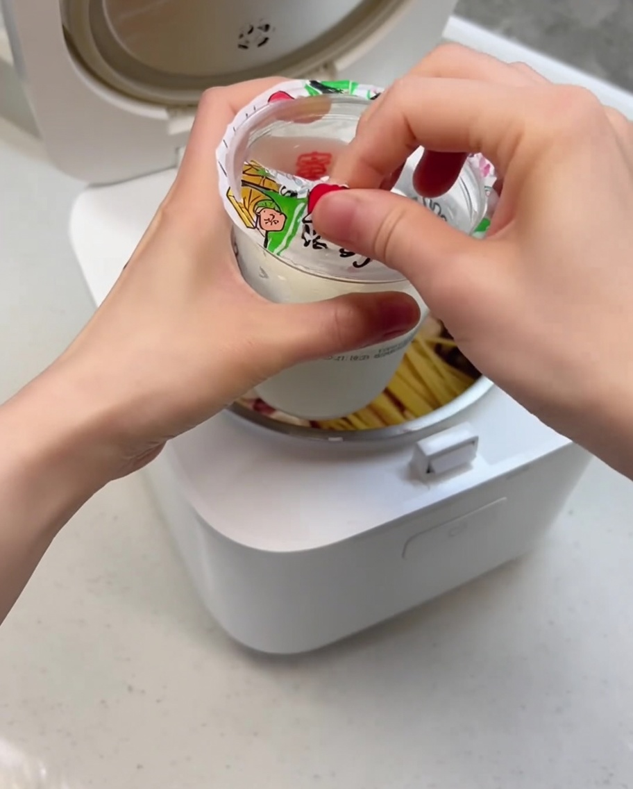 Primer plano del helado siendo vertido en la olla arrocera sobre los ingredientes.