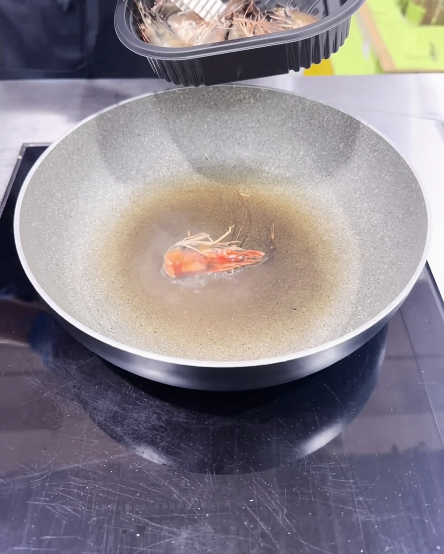 Cabezas de camarón siendo salteadas en una sartén para crear un aceite infundido.