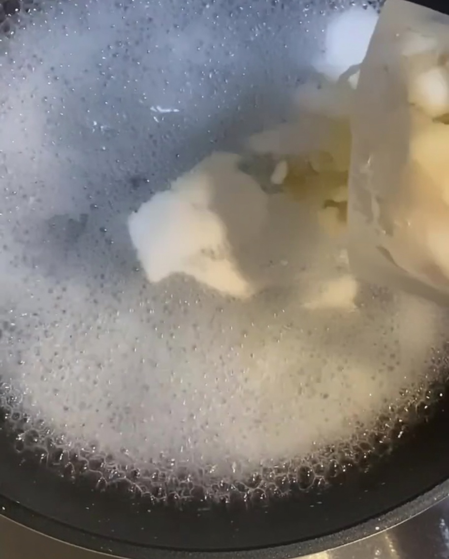 Camarones crudos siendo agregados a una olla de agua hirviendo, empezando a cambiar de color.