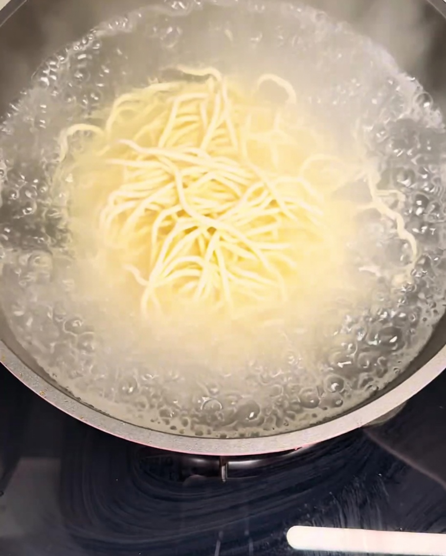 Fideos frescos sumergidos en una olla con agua hirviendo a borbotones.