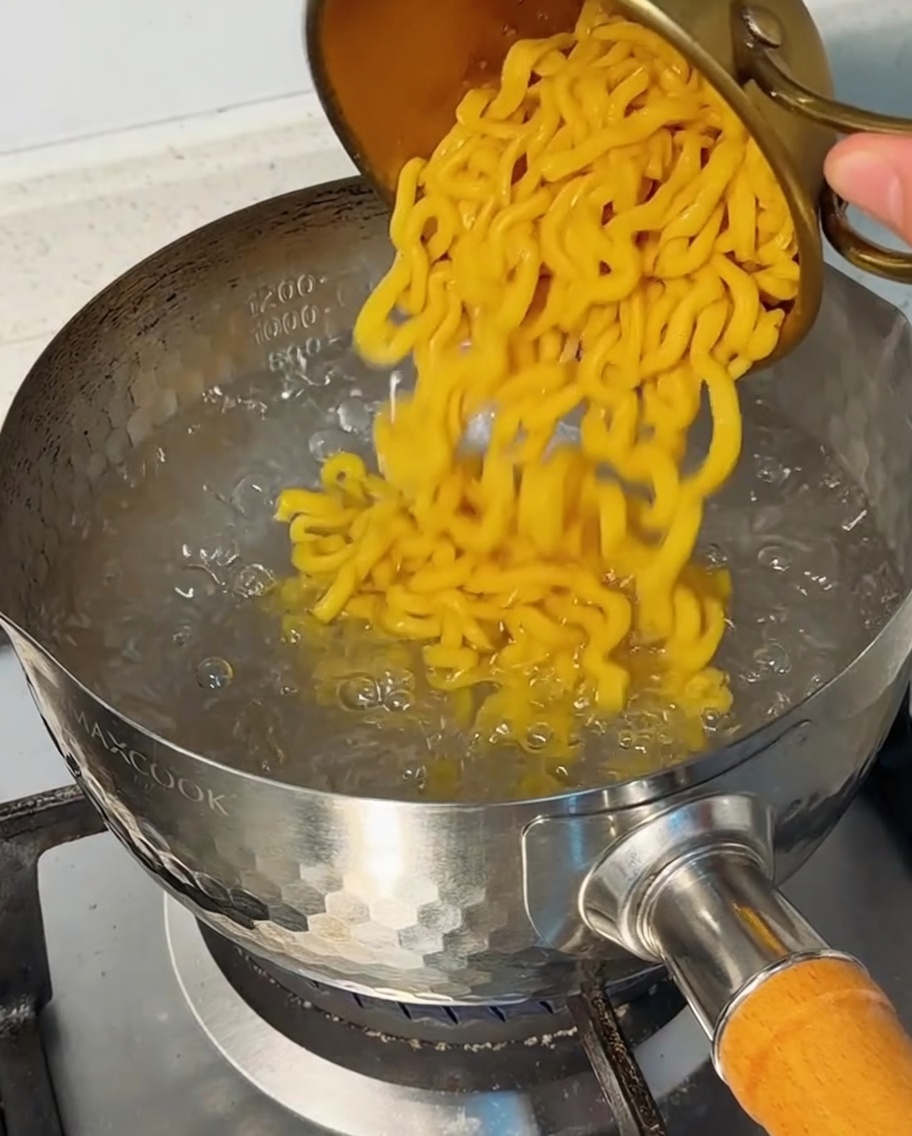 Macarrones vertiéndose en una olla con agua hirviendo.