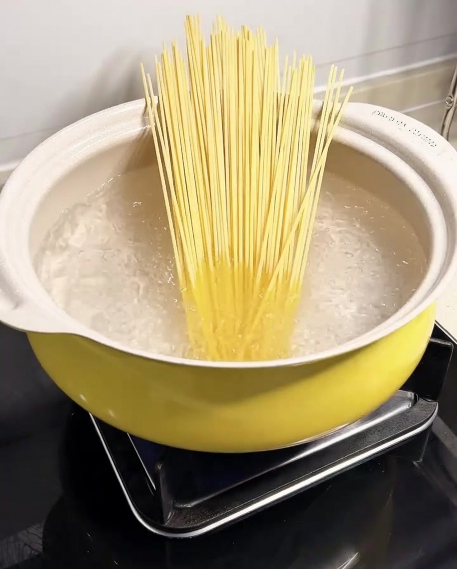 Espaguetis sumergidos en una olla con agua hirviendo.