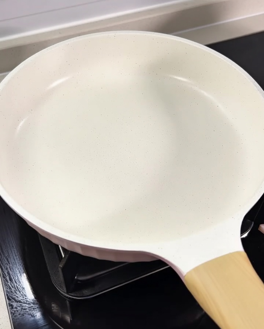 Guanciale en dados dorándose en una sartén blanca con su propia grasa.
