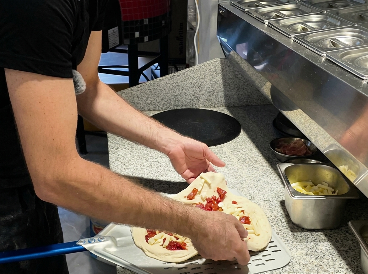 Pizza siendo introducida en el horno con una pala metálica.