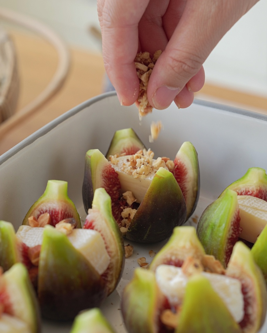 Higos rellenos en una fuente para hornear espolvoreados con frutos secos picados.