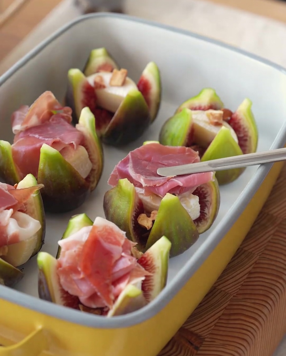 Higos rellenos coronados con lonchas de jamón y ramitas de romero fresco.