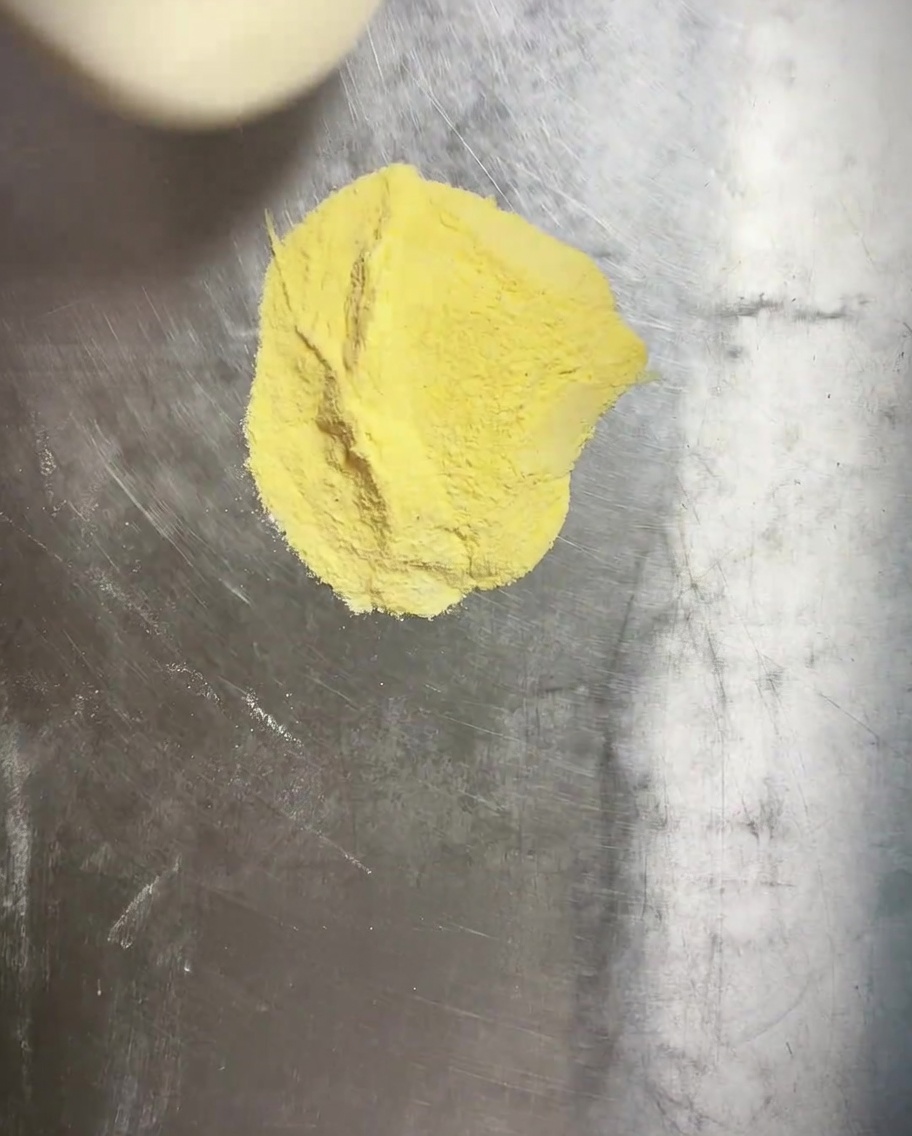 Masa de pizza siendo presionada en un molde redondo con una capa visible de harina de maíz debajo.