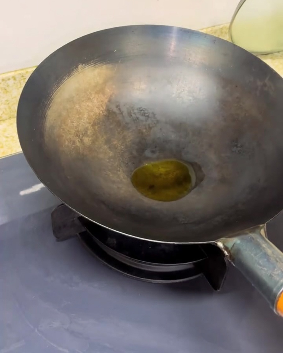 Tomates troceados cocinándose en un wok caliente, mostrando vapor y reducción de líquido.