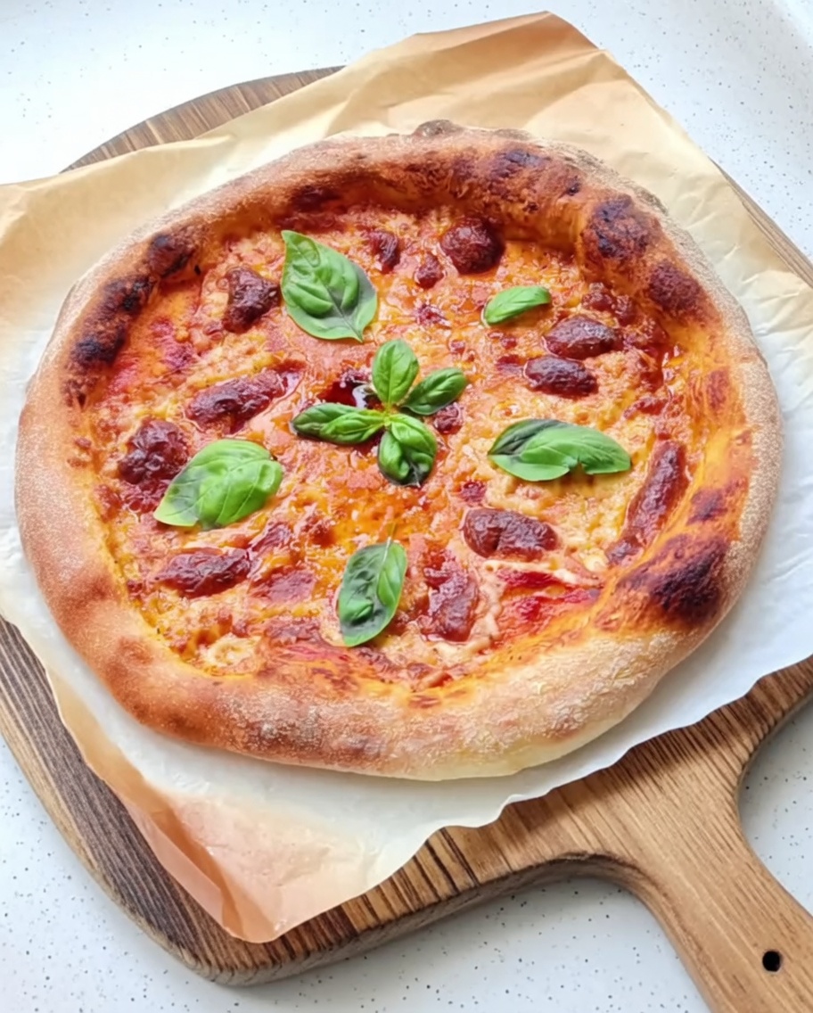 Salsa de tomate italiana siendo extendida uniformemente sobre una base de pizza redonda.