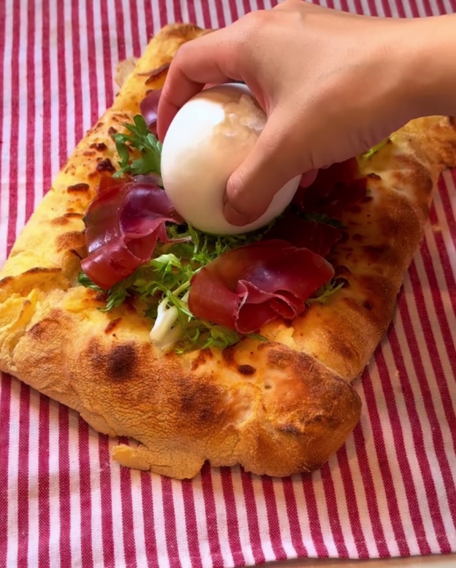 Una bola de burrata en el centro de la pizza con un chorrito de balsámico.