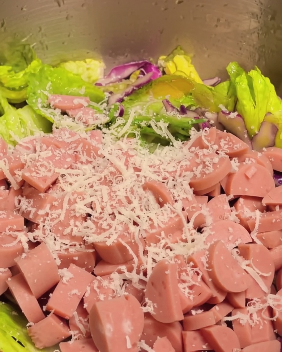 Jamón en dados y queso parmesano rallado añadiéndose a la mezcla de verduras para la ensalada.