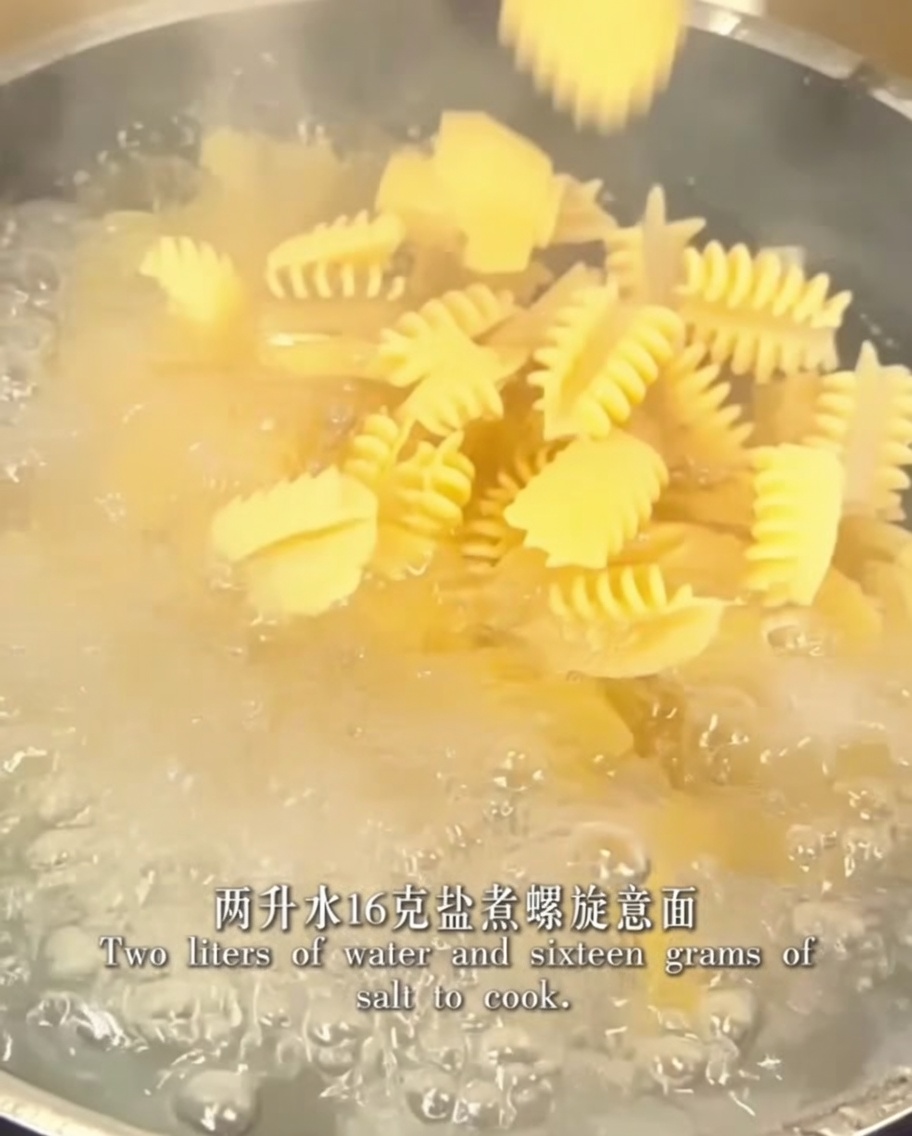 Pasta en espiral cociéndose en una olla con agua salada hirviendo.