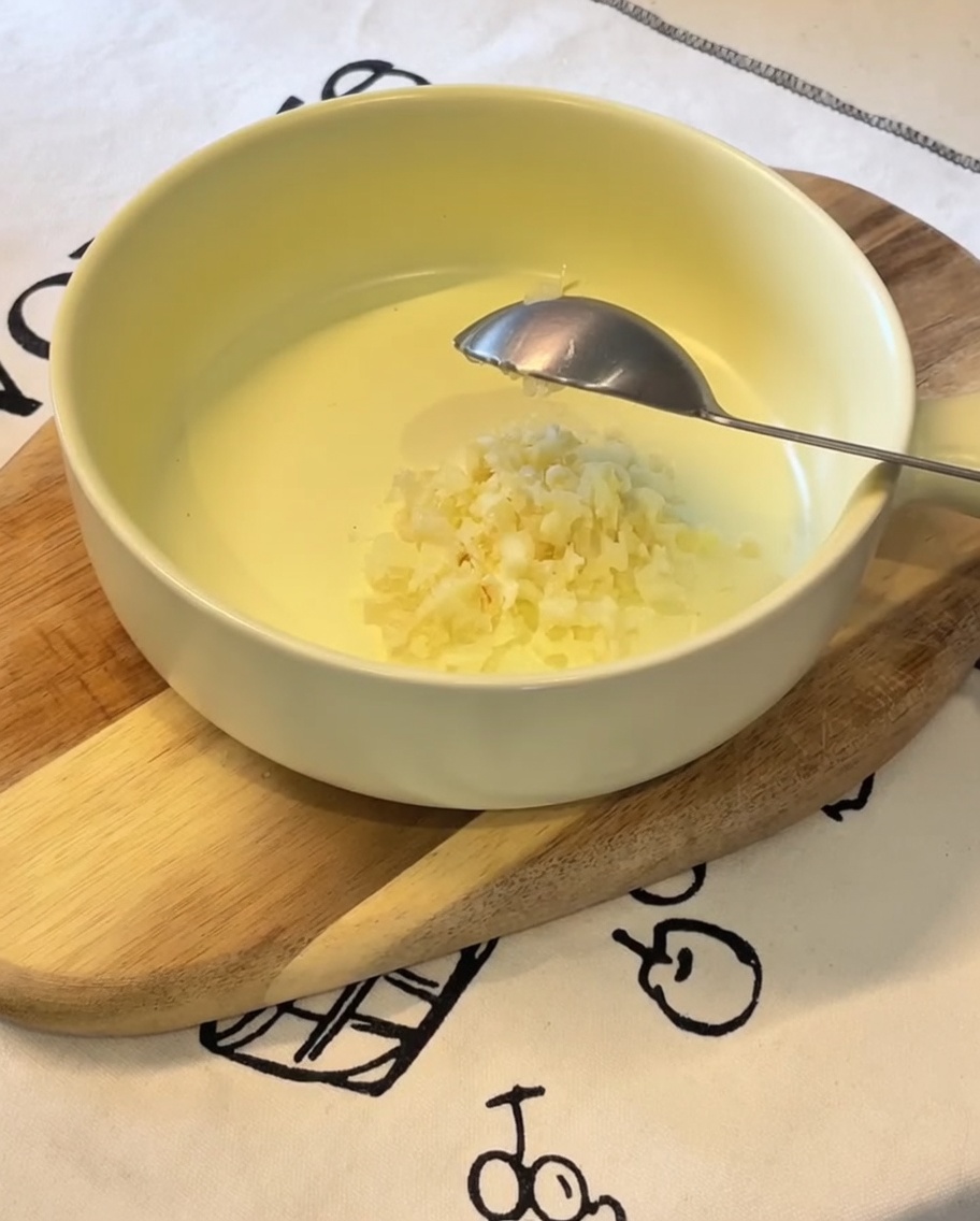 Ajo picado, cebollín en rodajas, mayonesa japonesa, una yema de huevo y polvo de condimento ramen en un tazón amarillo.