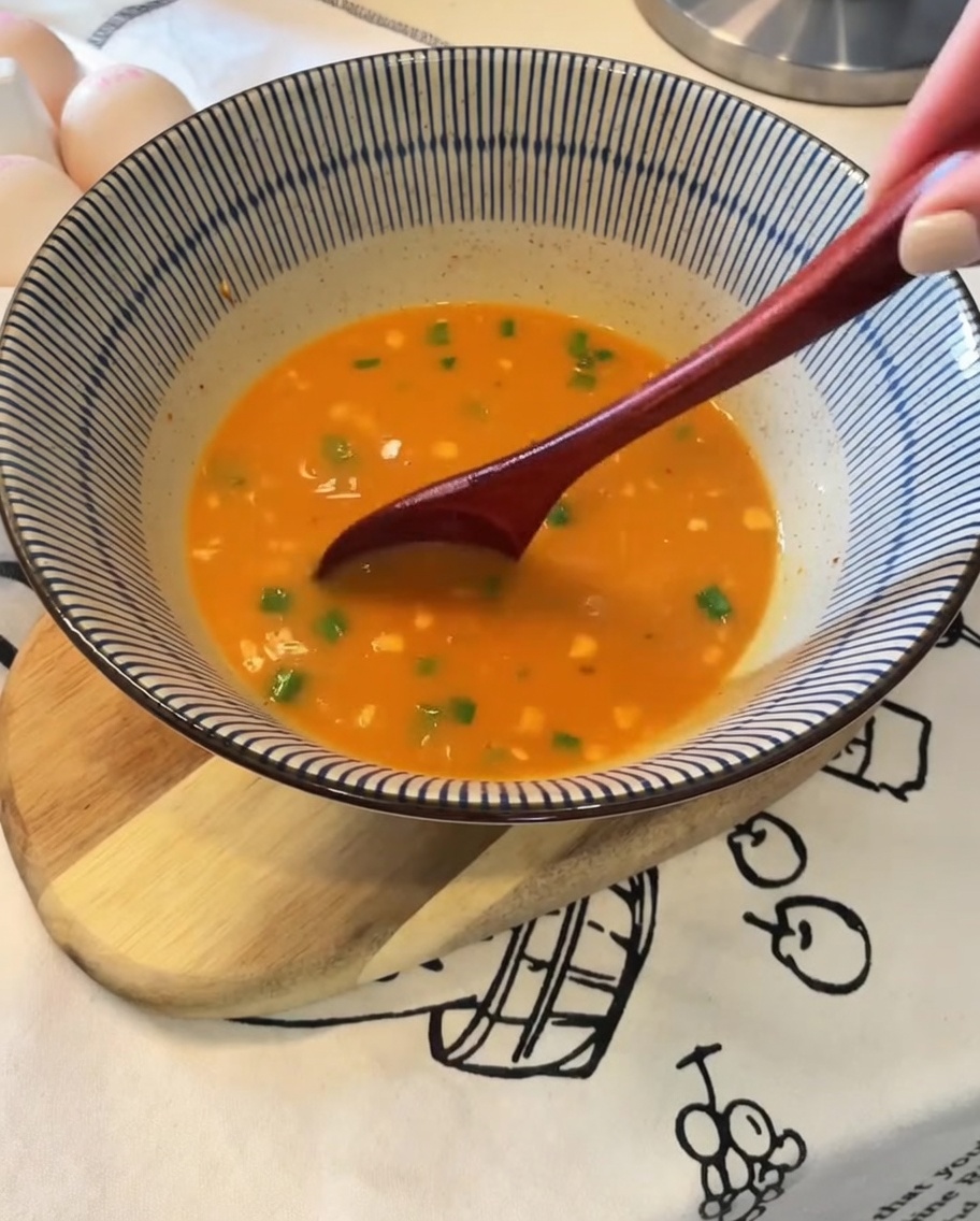 Fideos levantados con pinzas de una olla y colocados en un tazón de caldo sazonado.