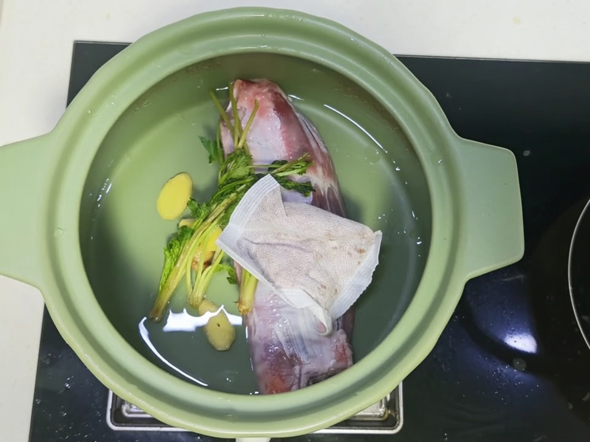 Una olla de barro llena de carne, especias y una mezcla de caldo oscuro y sabroso.