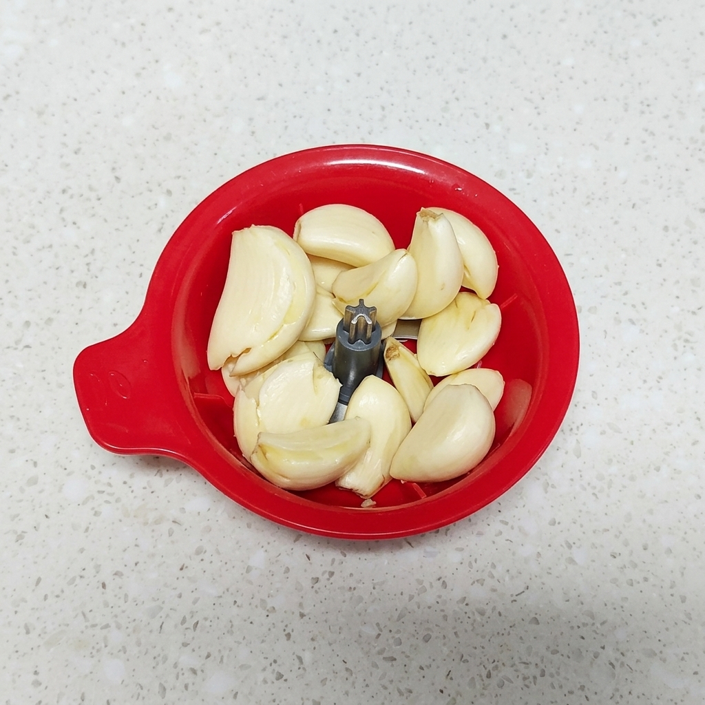 Dientes de ajo dentro de un pequeño picador manual de alimentos.