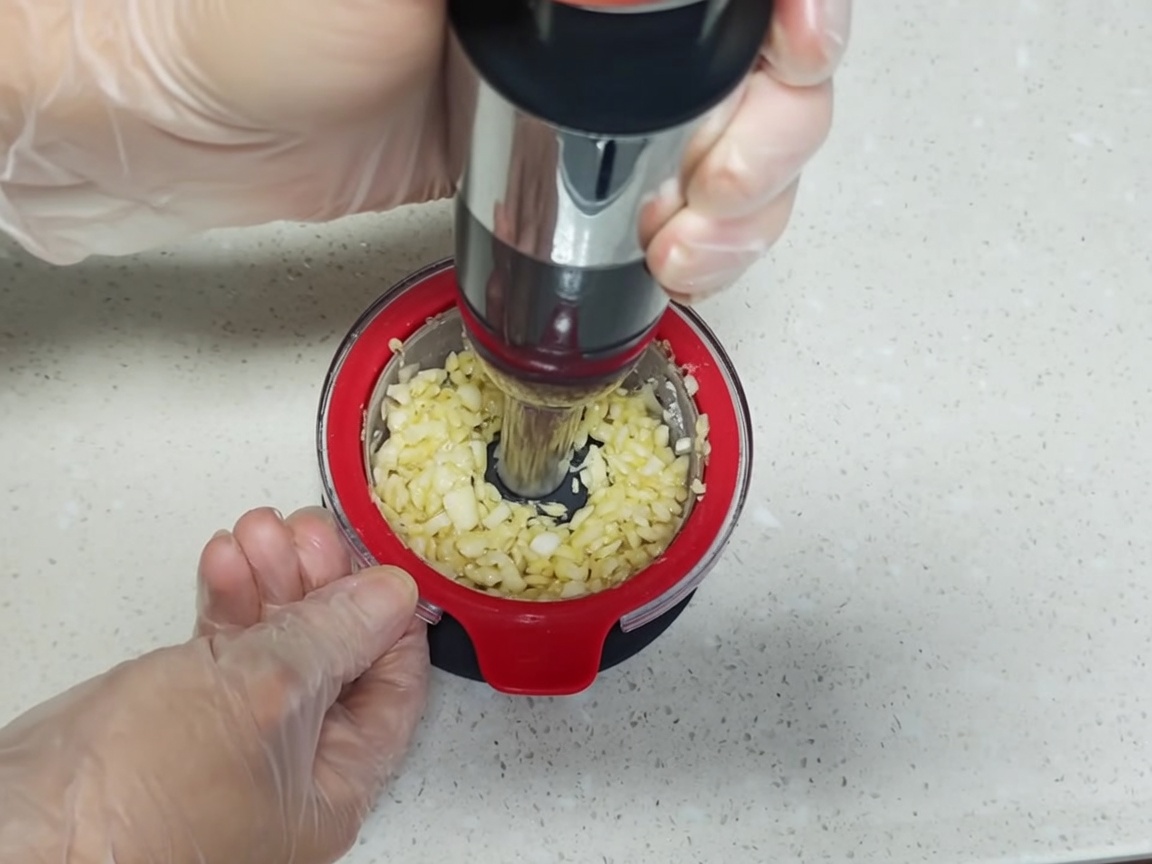 Un recipiente de acero inoxidable con huevos cocidos, aromáticos y una marinada a base de soja.
