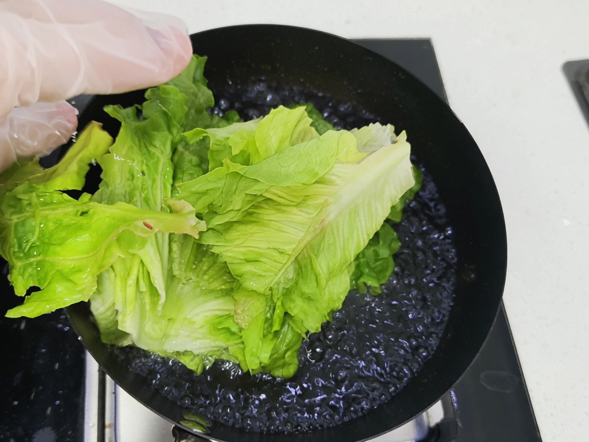 Verduras de hoja verde siendo sumergidas en una olla de agua hirviendo.