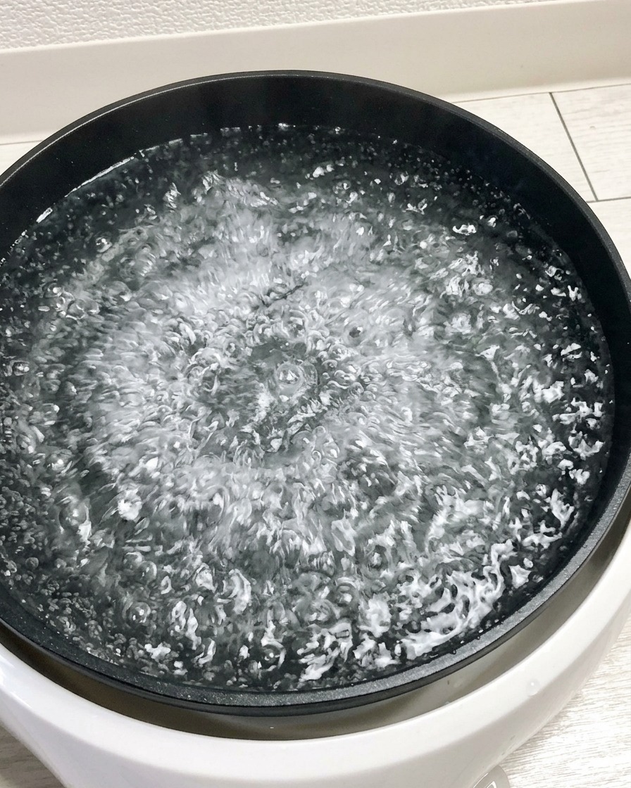 Huevos crudos siendo introducidos en una olla con agua hirviendo.