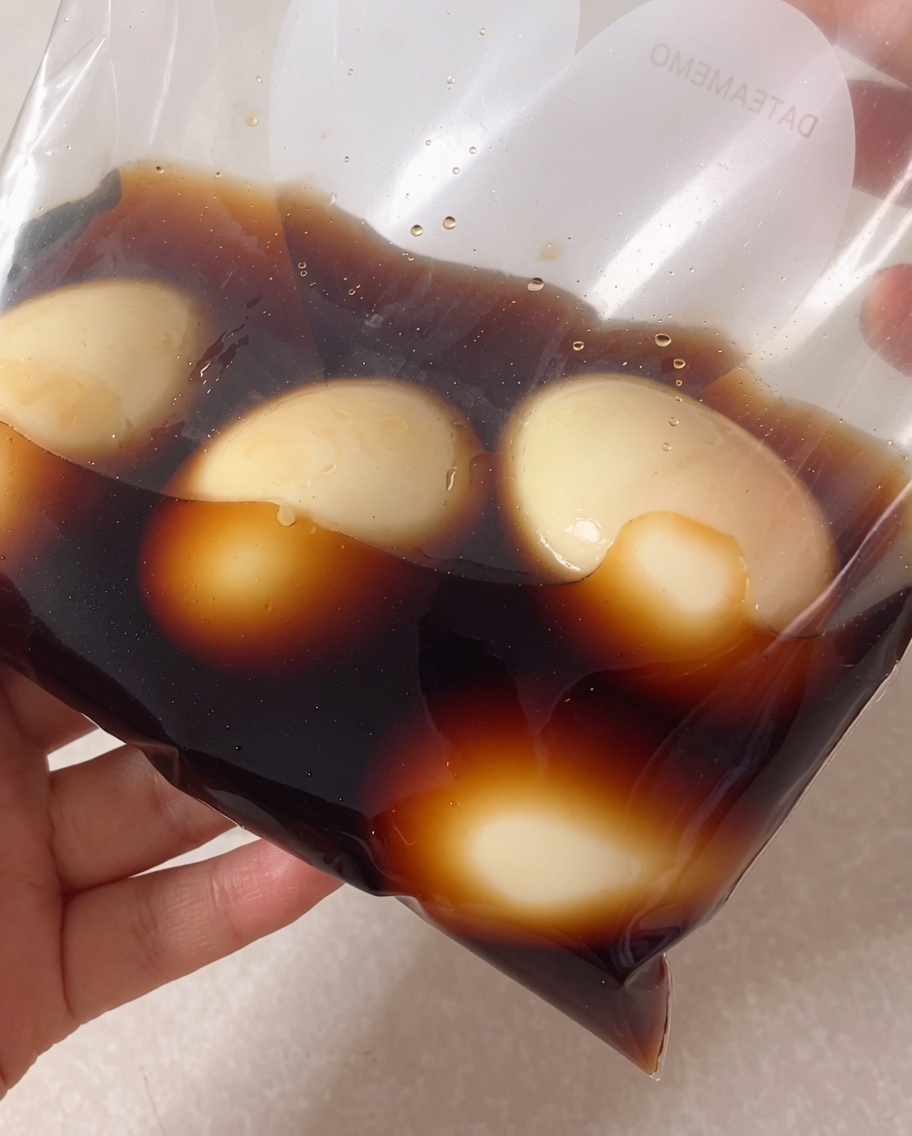 Huevos pelados en una bolsa de plástico siendo cubiertos con la marinada de soja.