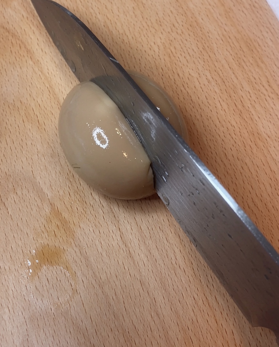 Un huevo marinado cortado por la mitad mostrando una yema cremosa.