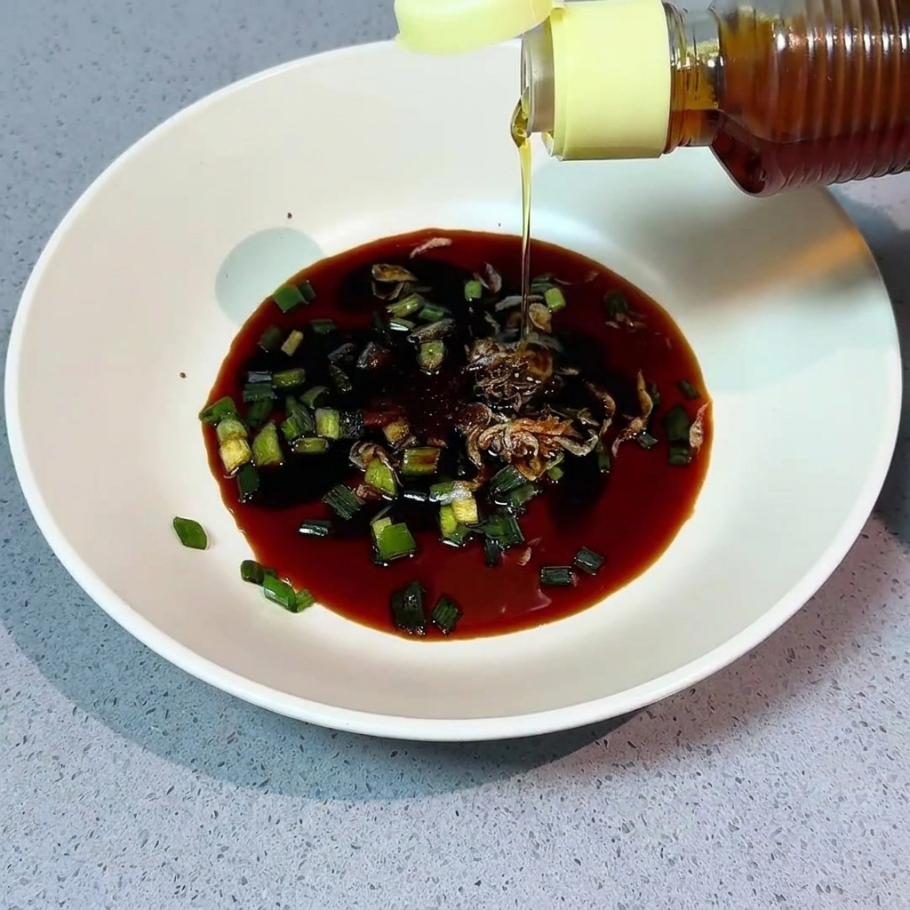 Aceite de sésamo siendo vertido desde una botella en un cuenco con condimentos.