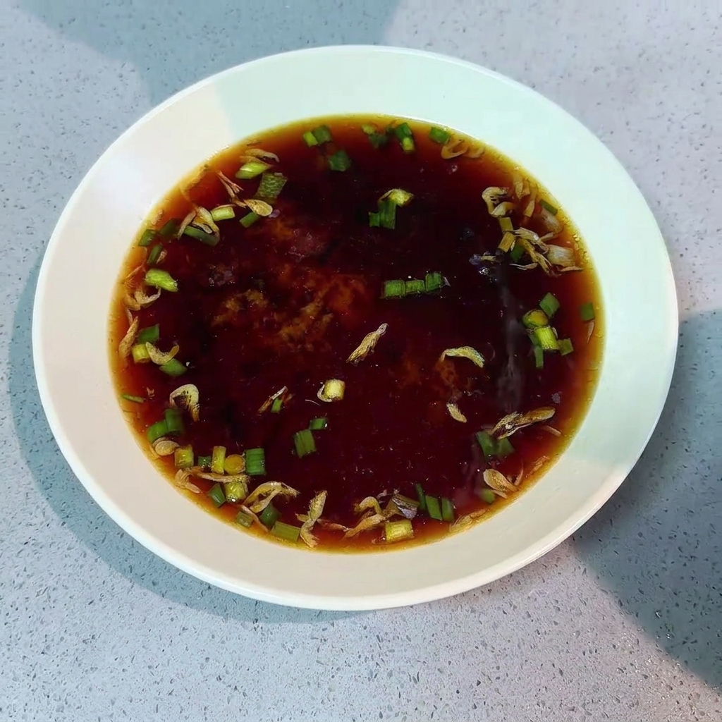 Fideos cocidos siendo transferidos de una olla a un cuenco con base de sopa.