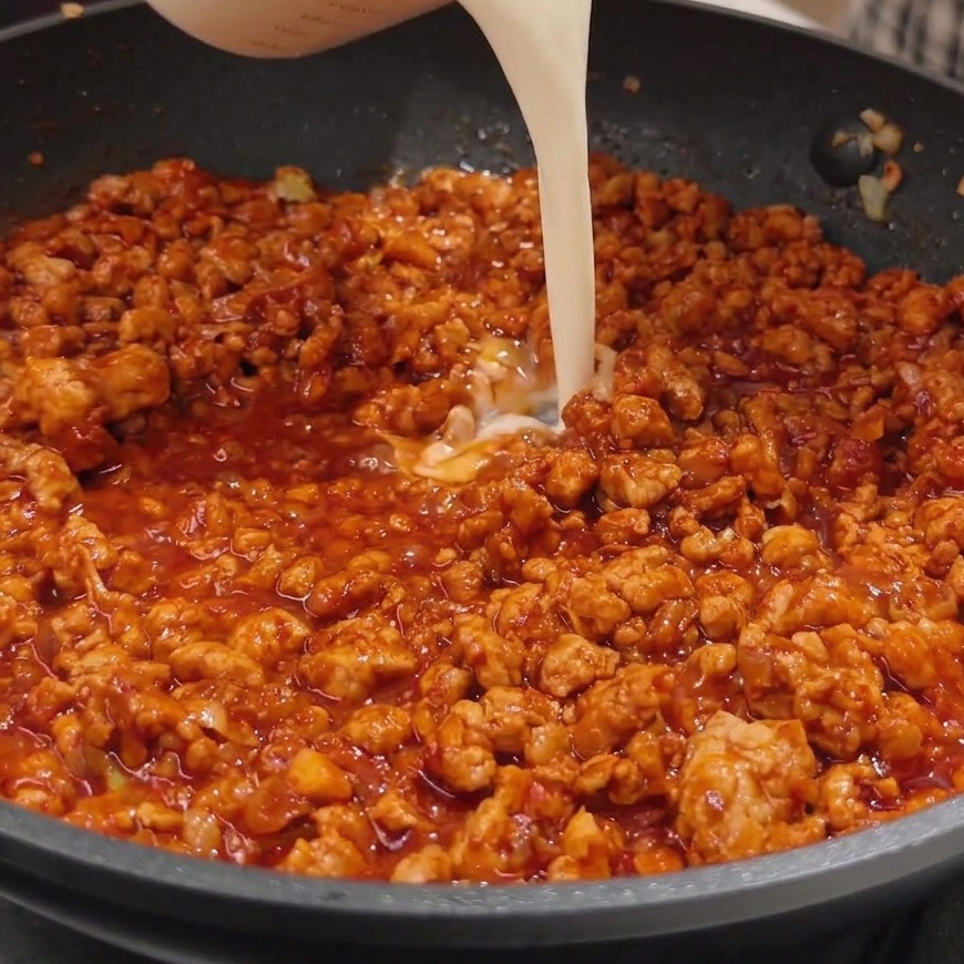 Leche de soja siendo vertida en la sartén con la salsa de miso y carne.
