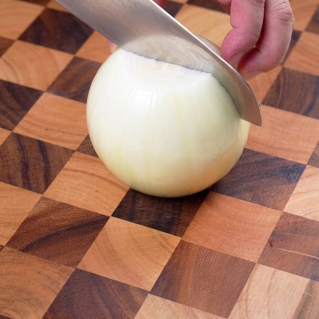 Cebolla amarilla cortada cuidadosamente en tiras finas sobre una tabla de madera.