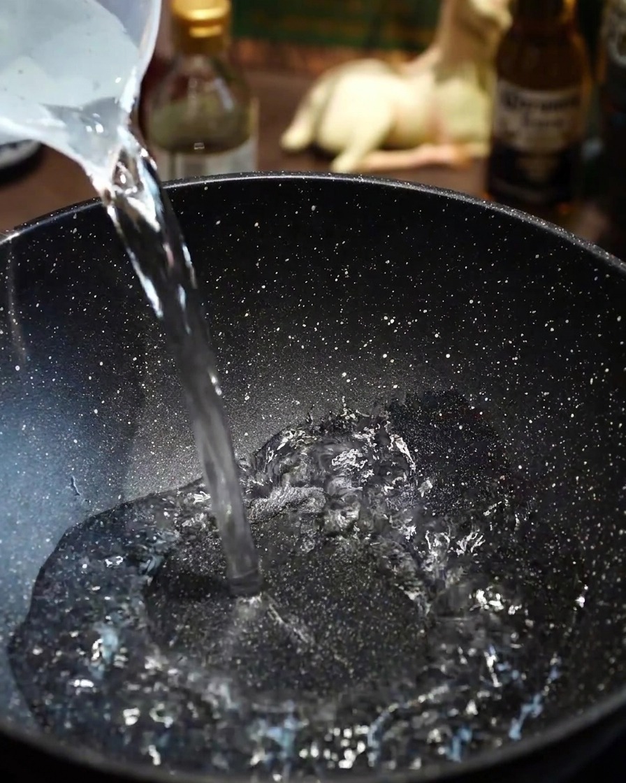 Láminas finas de ternera Wagyu añadidas con cuidado al agua hirviendo en una sartén.